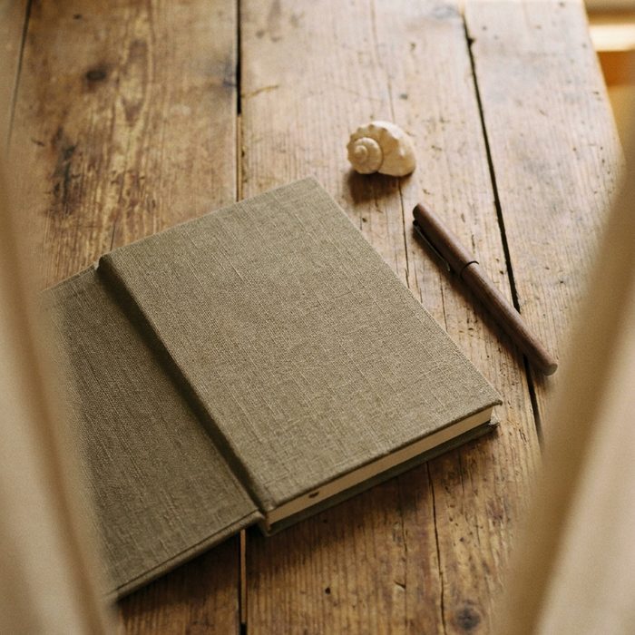 Freebie erstellen mit künstlicher Intelligenz: Geschlossenes Notizbuch mit Stift auf grauem Holz