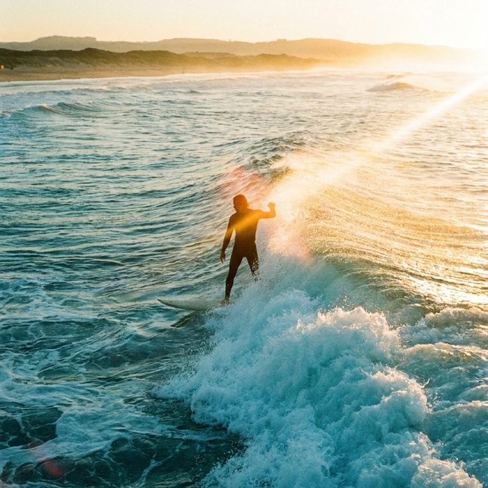 Business Motivation: Surferin auf einer Welle im goldenen Abendlicht
